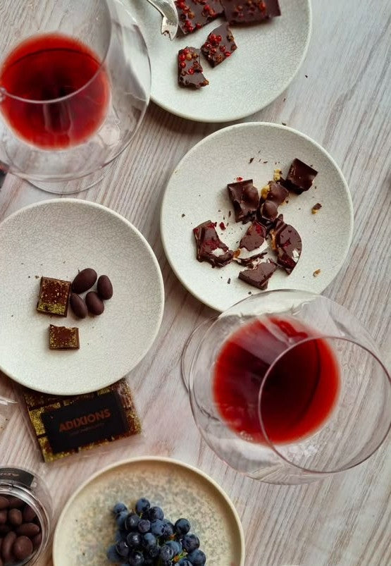 Choklad och rött vin uppdukat på små tallrikar med blåbär och mandlar