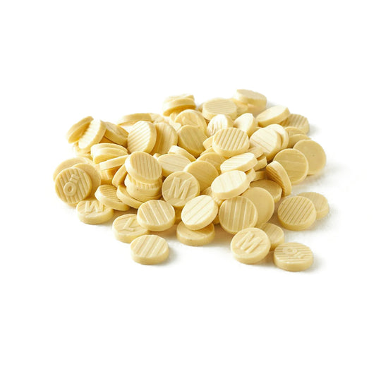 Nära bild av krämfärgade vita chokladpellets med M-märke