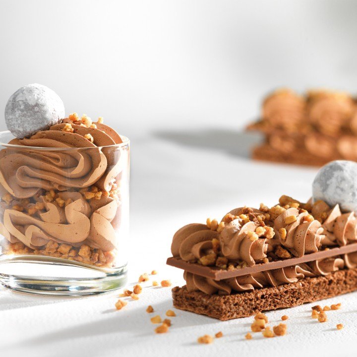 Callebaut mjölkchokladmousse pipad i snirvlar i glas med biskvitkrumor