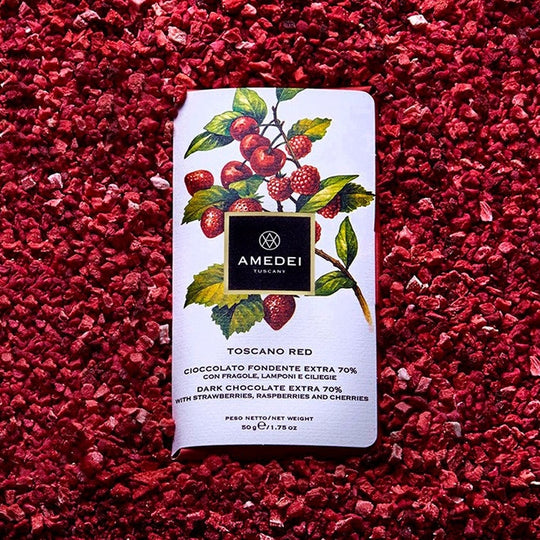 Chokladshopen Amedei Toscano Red mörk choklad 70% med frystorkade jordgubbar, hallon och körsbär på en bädd av bär.