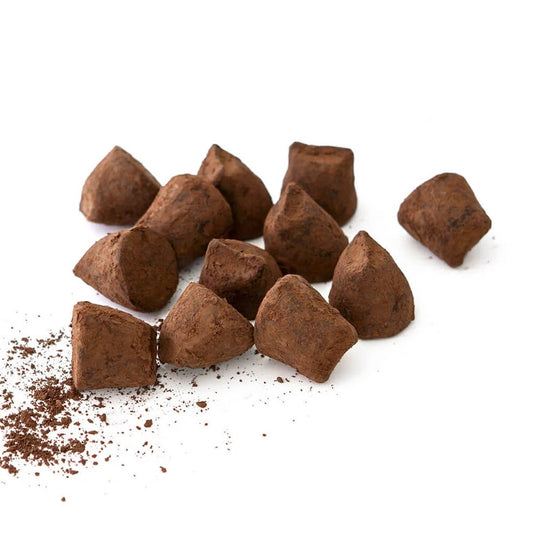 Chokladshopen La Praline tryfflar med saltkola pudrade med kakao på vit bakgrund